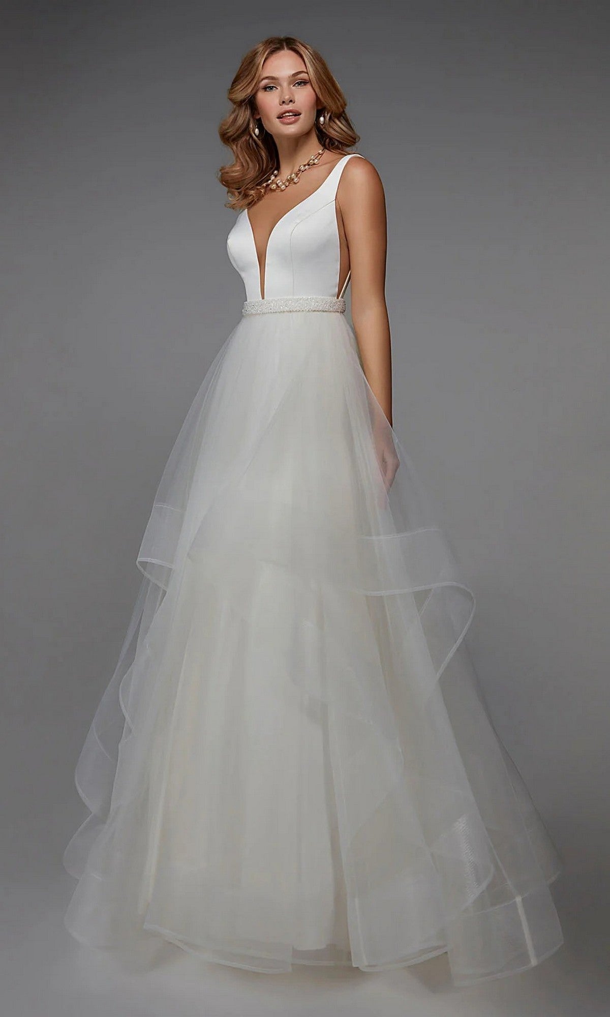 A woman wears the Alyce 7022 long white dress, featuring a sleeveless deep V-neckline, fitted bodice, beaded waistband, and an elegant A-line tulle skirt.
